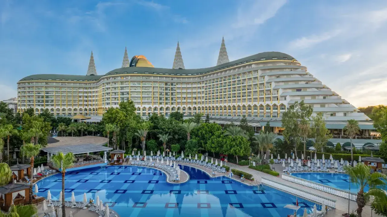 Luksusowy hotel Delphin Imperial Lara z basenem i leżakami, otoczony zielenią.