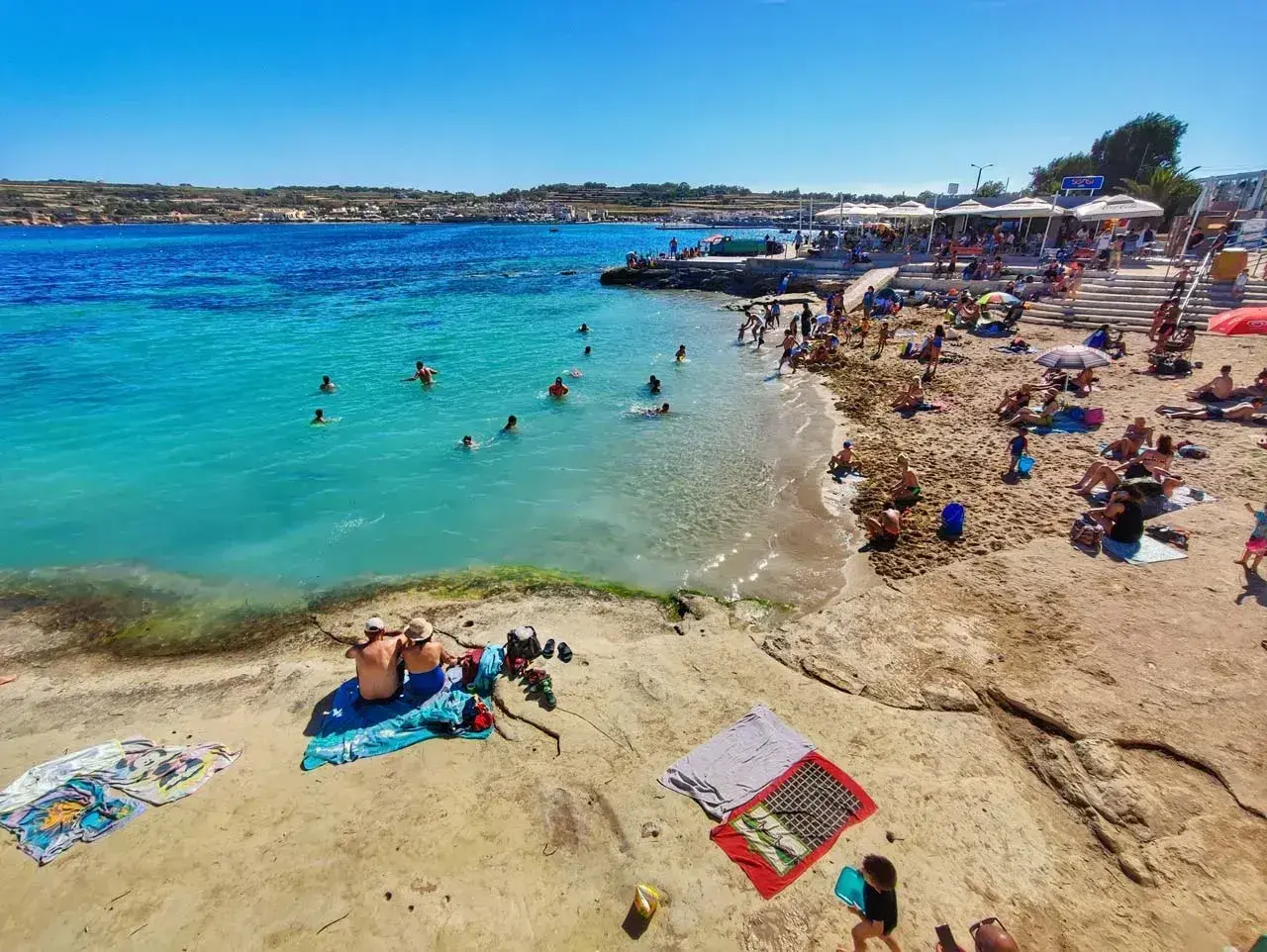 Malta pogoda w maju: słoneczny dzień nad turkusowym morzem, plażowicze kąpią się i opalają.