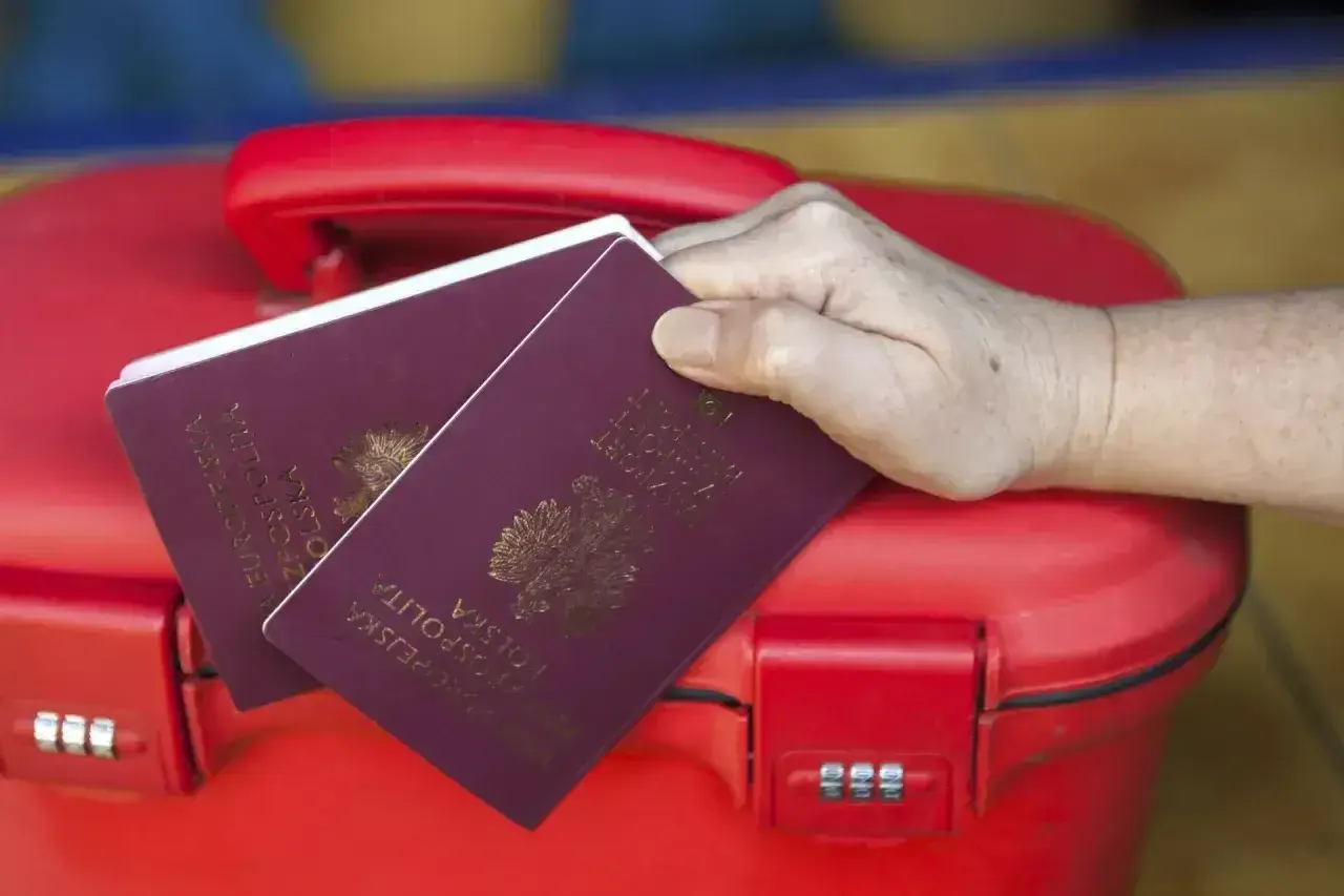 Dwa paszporty na czerwonej walizce. Zastanawiasz się, paszport dla dziecka ile ważny?