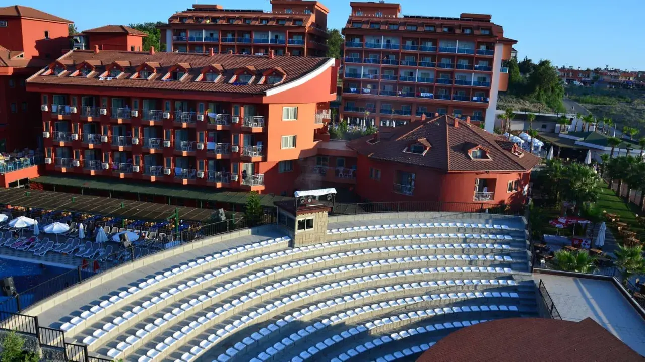 Amfiteatr z białymi siedzeniami i hotelami w tle, idealne miejsce na wieczorne pokazy w club side coast.