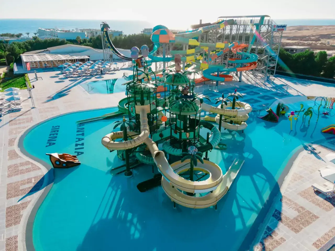 Kolorowy aquapark Fantazia Resort Marsa Alam z licznymi zjeżdżalniami i basenami, w tle morze.