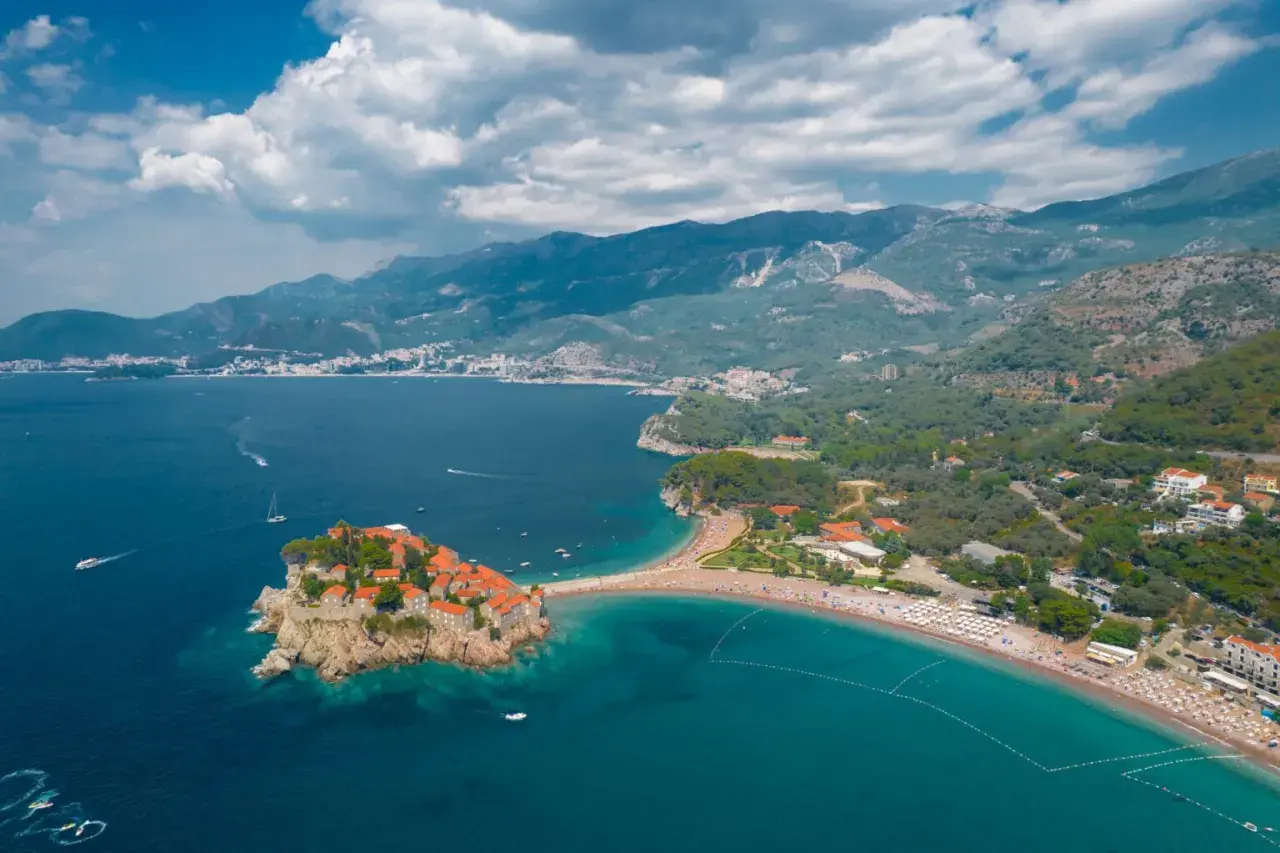 Sveti Stefan, Czarnogóra, idealna pogoda we wrześniu. Wyspa z kamiennymi domkami i plaża z turkusową wodą.