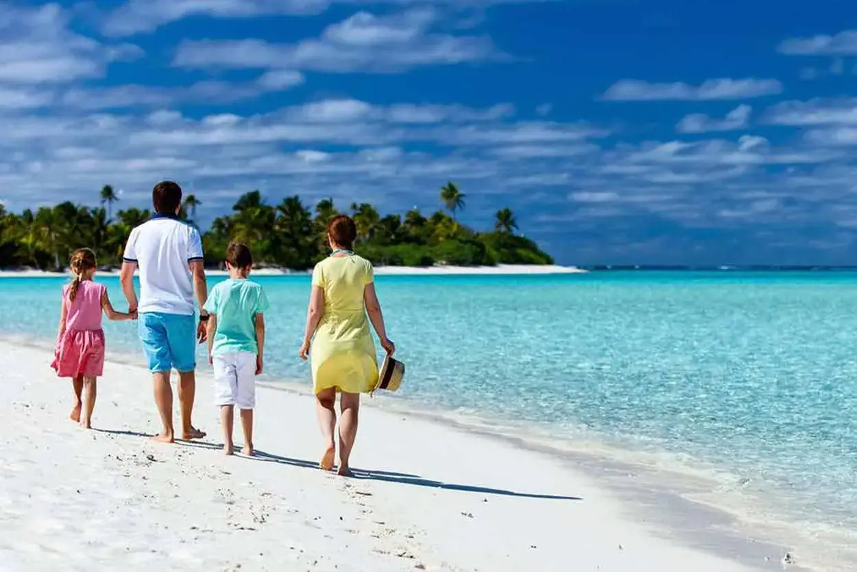 Rodzina spaceruje po rajskiej plaży. Idealne wakacje z dziećmi gdzie? Na pewno tutaj!
