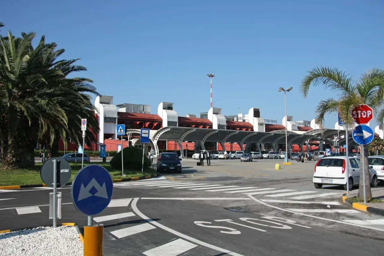 Lamezia Terme lotnisko, z palmami i samochodami przed nowoczesnym budynkiem terminalu.
