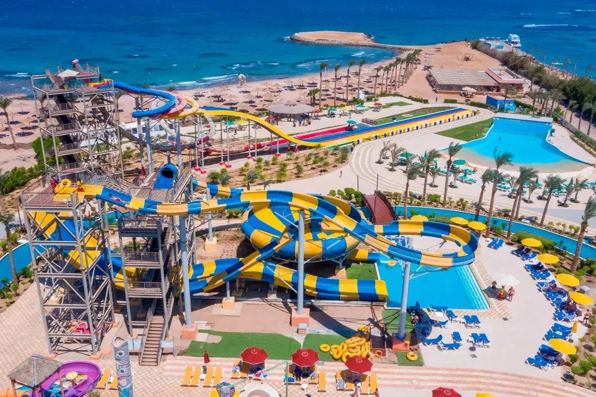 Wodne zjeżdżalnie w Blend Club Aqua Resort kuszą kolorami i zabawą. Widać plażę i turkusowe morze.