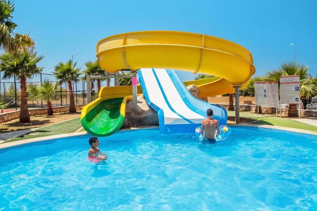 Dzieci bawią się w basenie przy zjeżdżalniach wodnych w **garden of sun spa & wellness**.