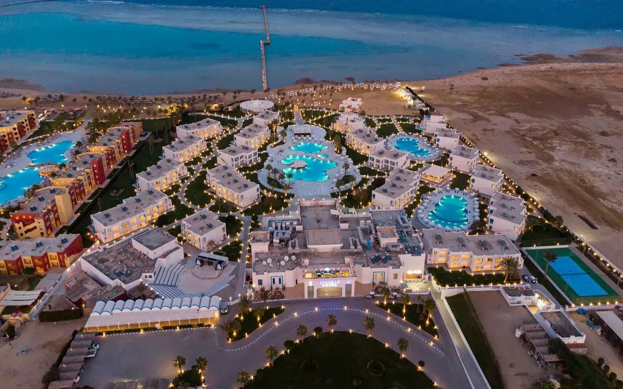 Widok z lotu ptaka na luksusowy resort Casa Blue, z basenami, budynkami i morzem w tle, oświetlony wieczorem.