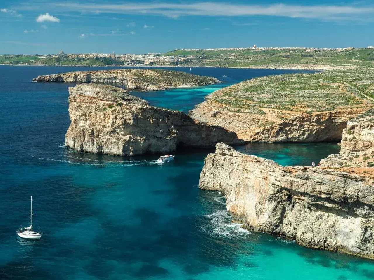 Malta we wrześniu: turkusowa woda, skaliste wybrzeże i łodzie. Idealna pogoda na zwiedzanie.