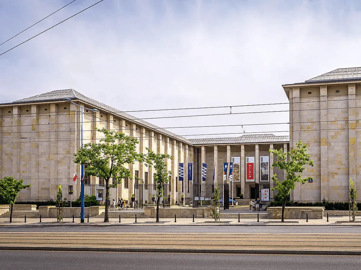 Muzeum Narodowe w Warszawie – jedno z kluczowych warszawa miejsca do zwiedzania. Monumentalna budowla z flagami i drzewami przed wejściem.