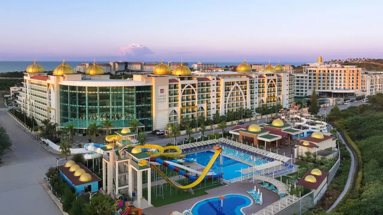 Luksusowy Alan Xafira Deluxe Resort & Spa z basenami i zjeżdżalniami, w blasku zachodzącego słońca.