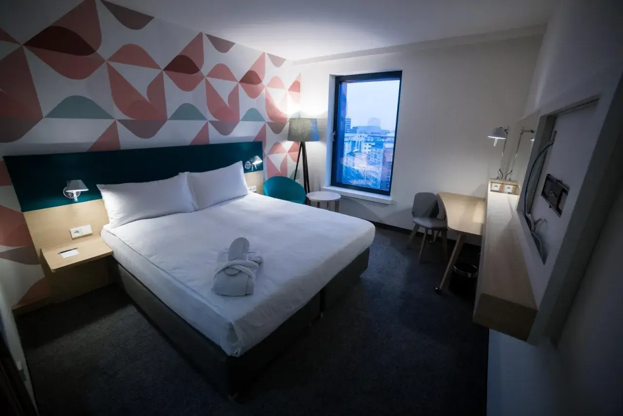 Przytulny pokój hotelowy z łóżkiem, szlafrokiem i widokiem na miasto. "Room only" to oferta bez wyżywienia.