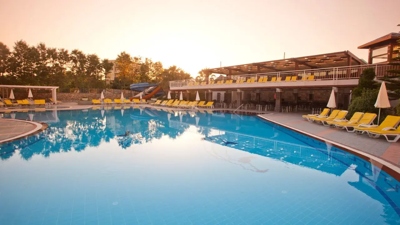 Basen w club mermaid village, z leżakami i zjeżdżalniami, w blasku zachodzącego słońca.