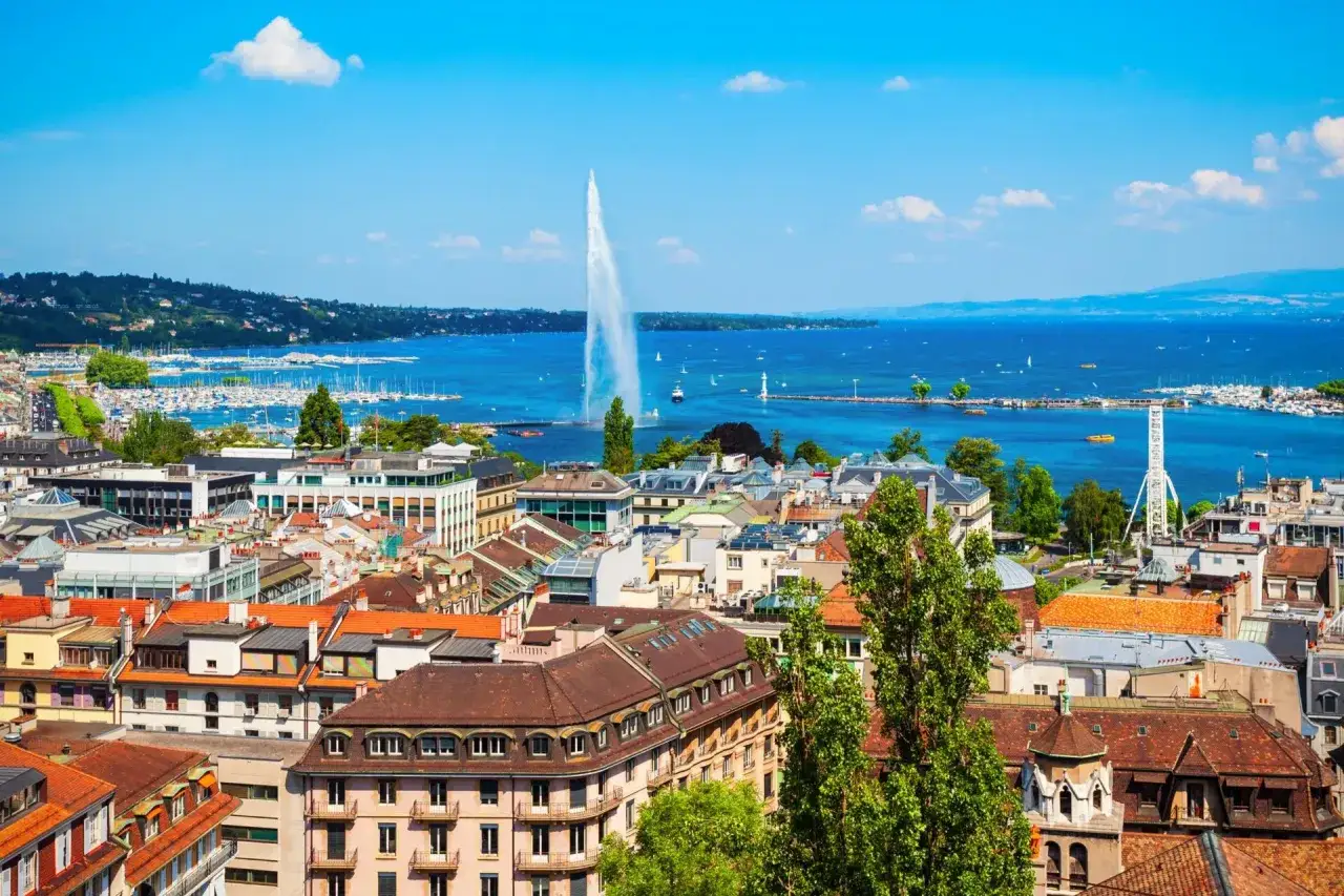 Widok na Jezioro Genewskie z Jet d'Eau, łodzie i miasto. Genewa co zobaczyć to m.in. ten imponujący widok.