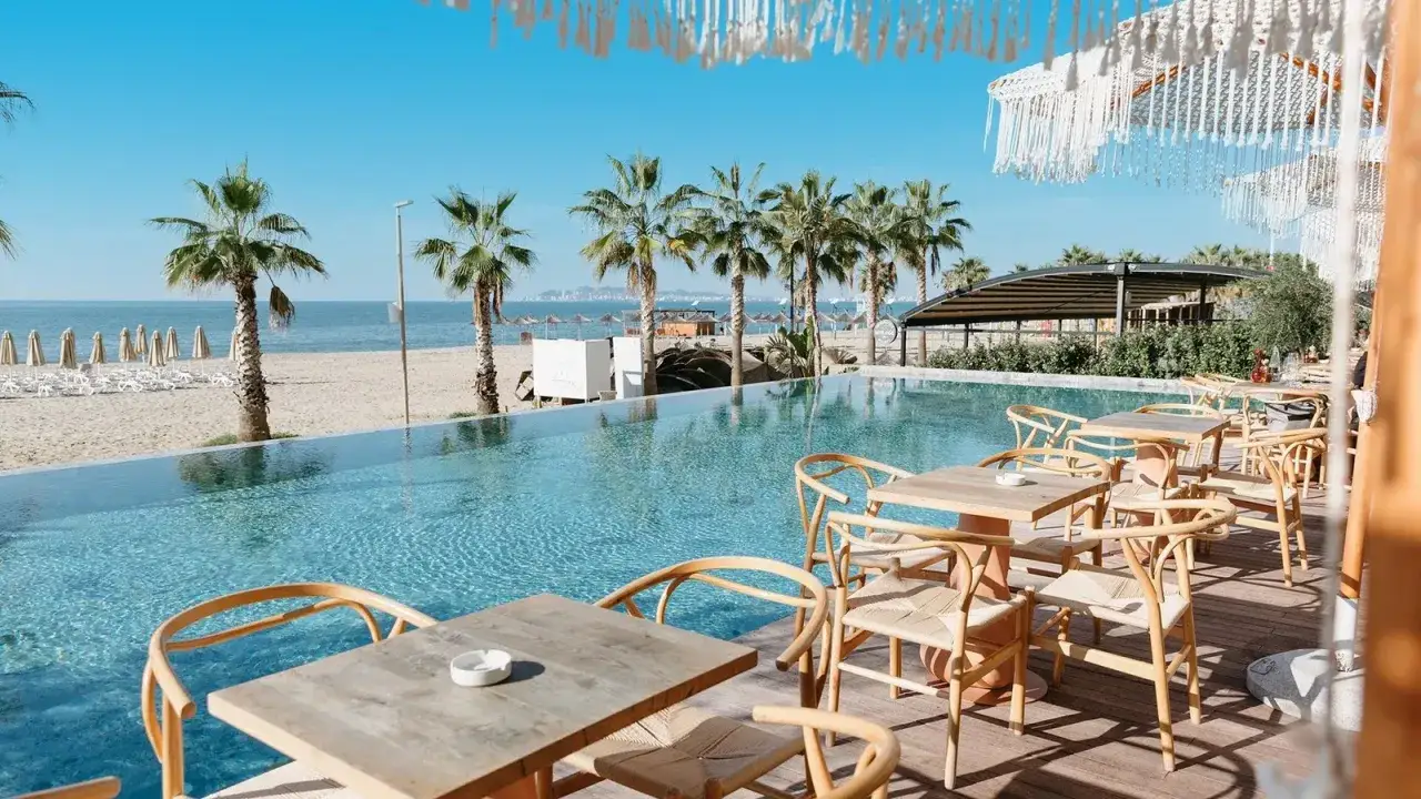 Relaks przy basenie z widokiem na plażę i palmy. Białe, zwiewne dekoracje tworzą epidamn white sensation.
