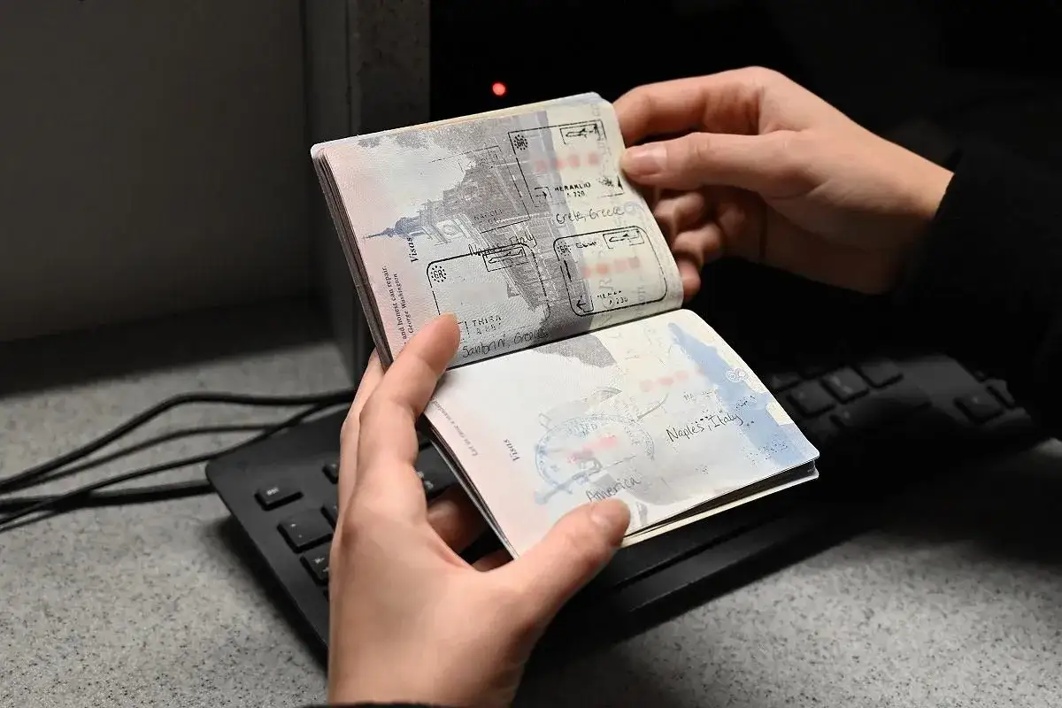 Ręce trzymają otwarty paszport z pieczątkami z podróży do Grecji i Włoch. Pokazuje, ile ważny jest paszport dla swobodnego podróżowania.