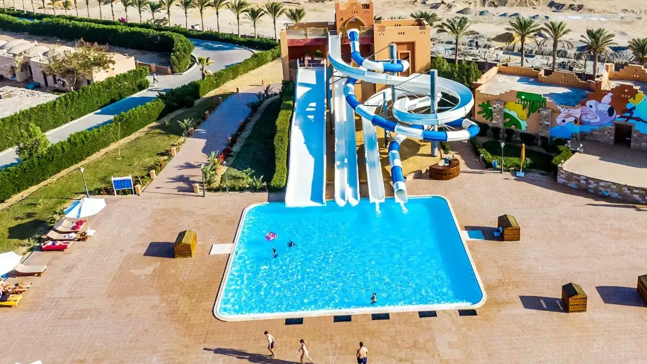 Wodne zjeżdżalnie i basen w Dream Lagoon & Aqua Park Resort. Dzieci bawią się w wodzie, dorośli odpoczywają na leżakach.