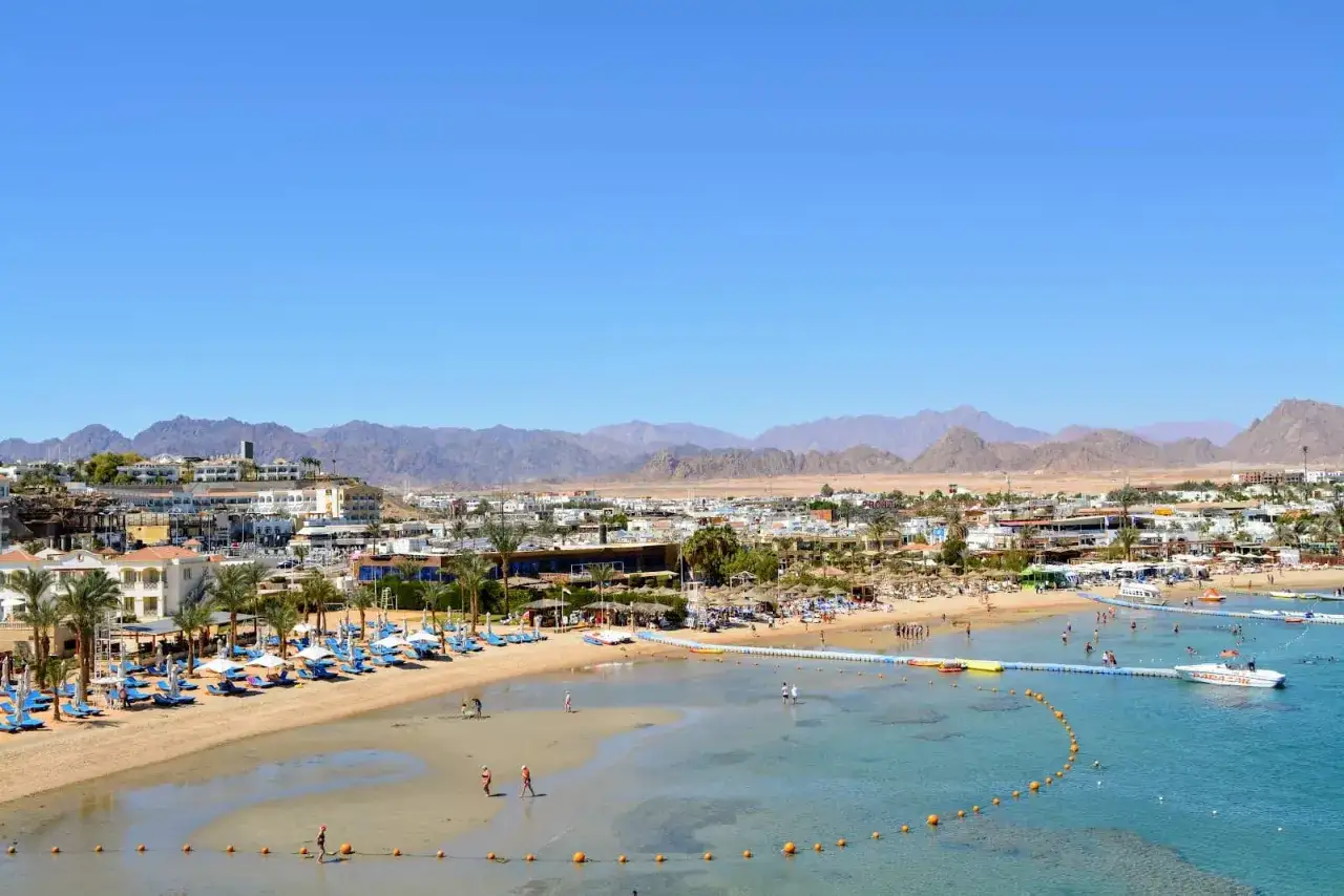 Widok na plażę i morze z hotelami w Sharm Grand Plaza Resort. W tle góry.
