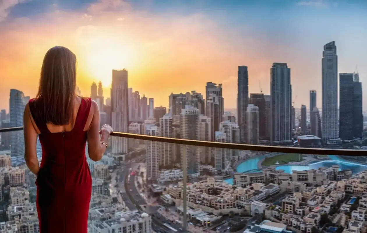 Kobieta w czerwonej sukience podziwia panoramę Dubaju o zachodzie słońca. Idealna dubaj pogoda maj, ciepło i piękne niebo.