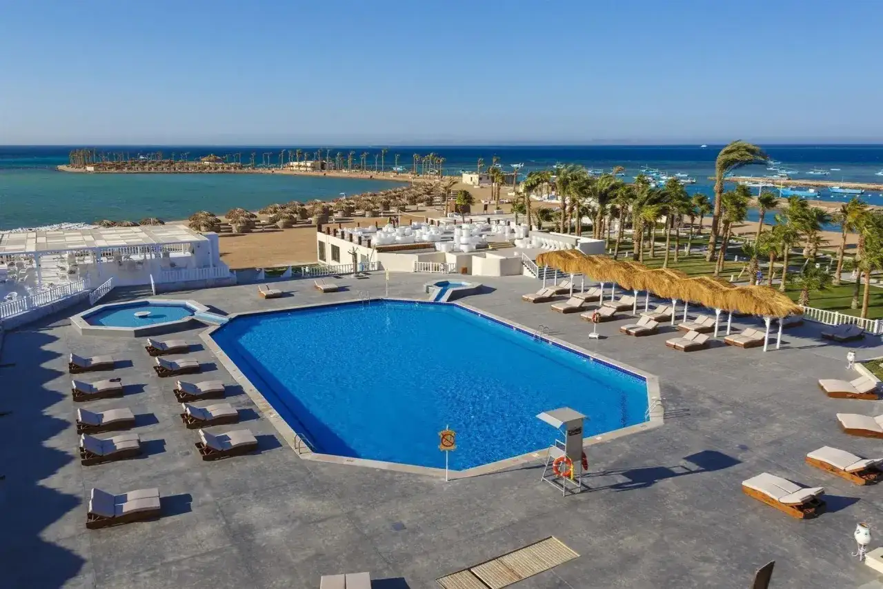 Basen i plaża w Meraki Resort Hurghada. Słoneczny dzień, palmy, leżaki i turkusowe morze.