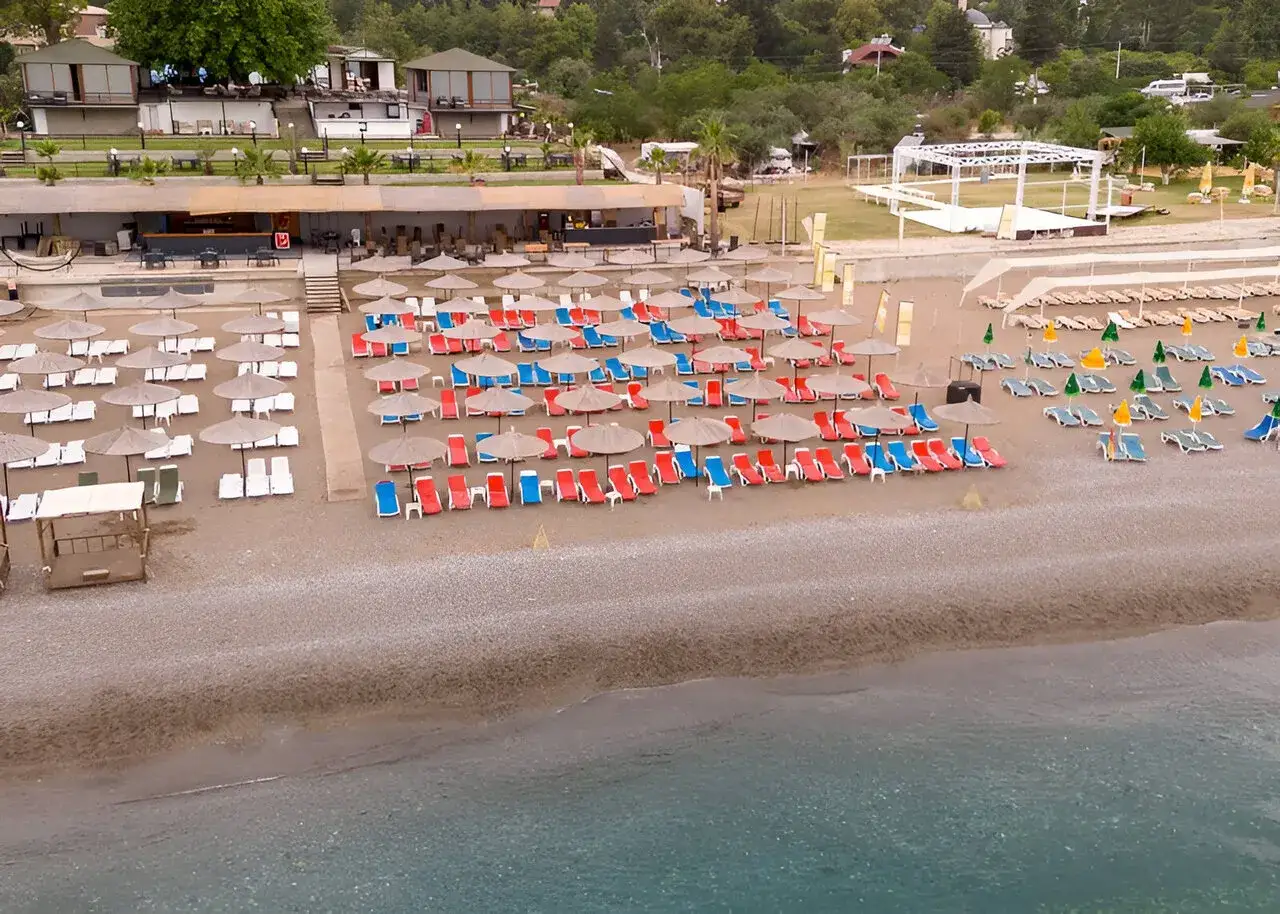 Plaża w Greenwood Kemer Resort z rzędami leżaków i parasoli.