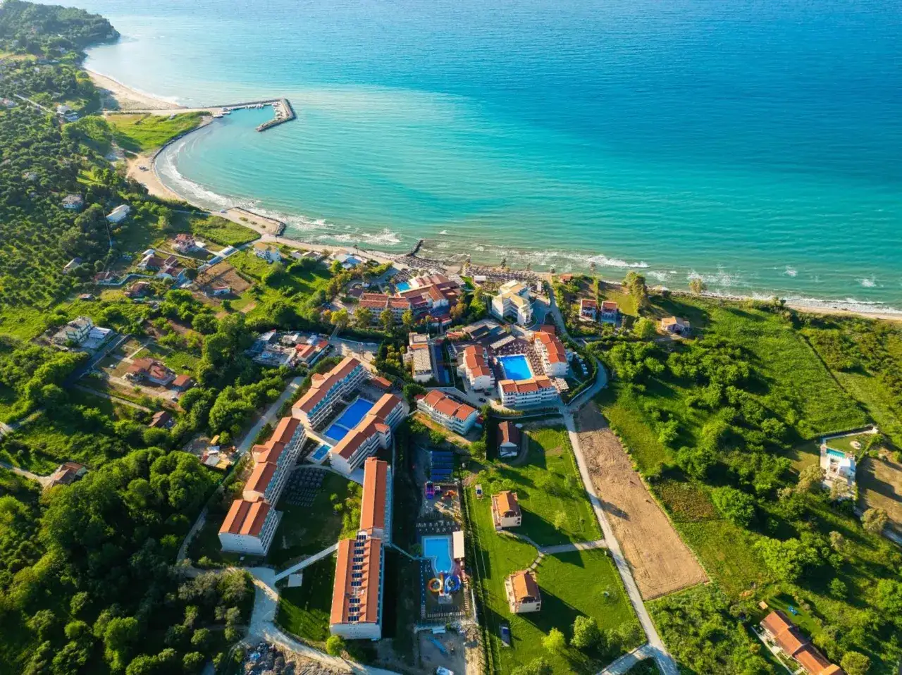 Widok z lotu ptaka na Angela Beach Korfu. Turkusowe morze, plaża, hotel z basenami i zielone wzgórza.