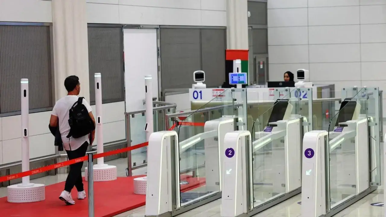 Mężczyzna z plecakiem idzie do bramek na lotnisku. Czy do Dubaju trzeba paszport? Tu widać automatyczne bramki, ale też pracownika obsługi.