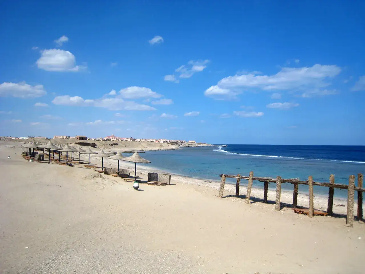 Piękna, słoneczna pogoda w Marsa Alam w maju. Pusta plaża z leżakami i parasolami, turkusowe morze i błękitne niebo.