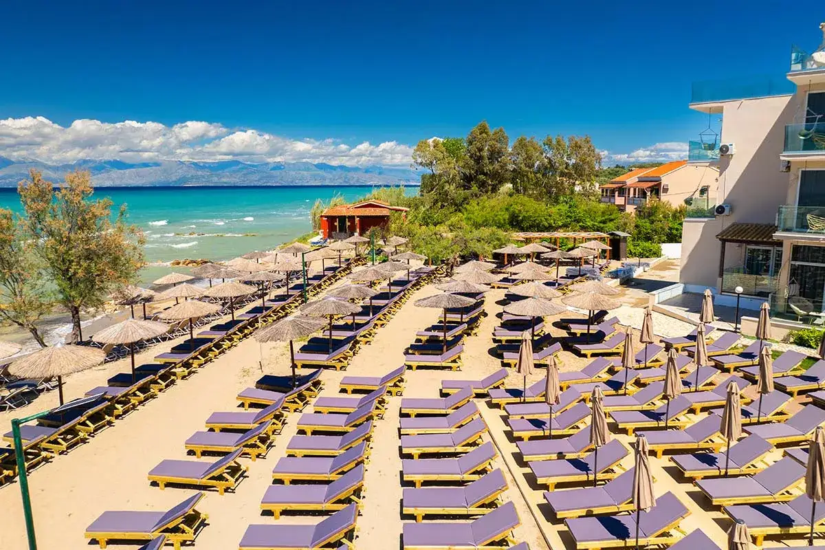 Piękna plaża Angela Beach na Korfu, z rzędami leżaków i parasoli, gotowa na gości.