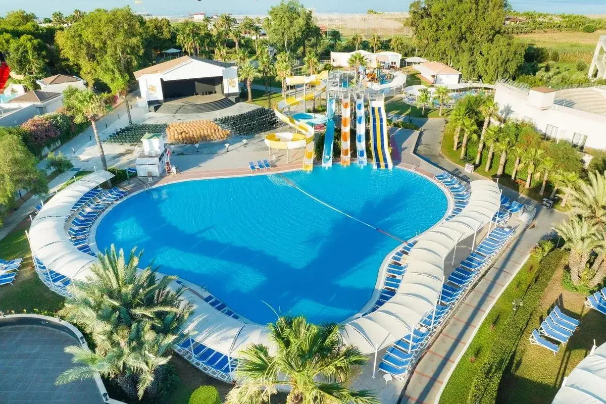 Wspaniały basen z wodnymi zjeżdżalniami, otoczony leżakami i palmami, idealne miejsce na wakacje na club side coast.