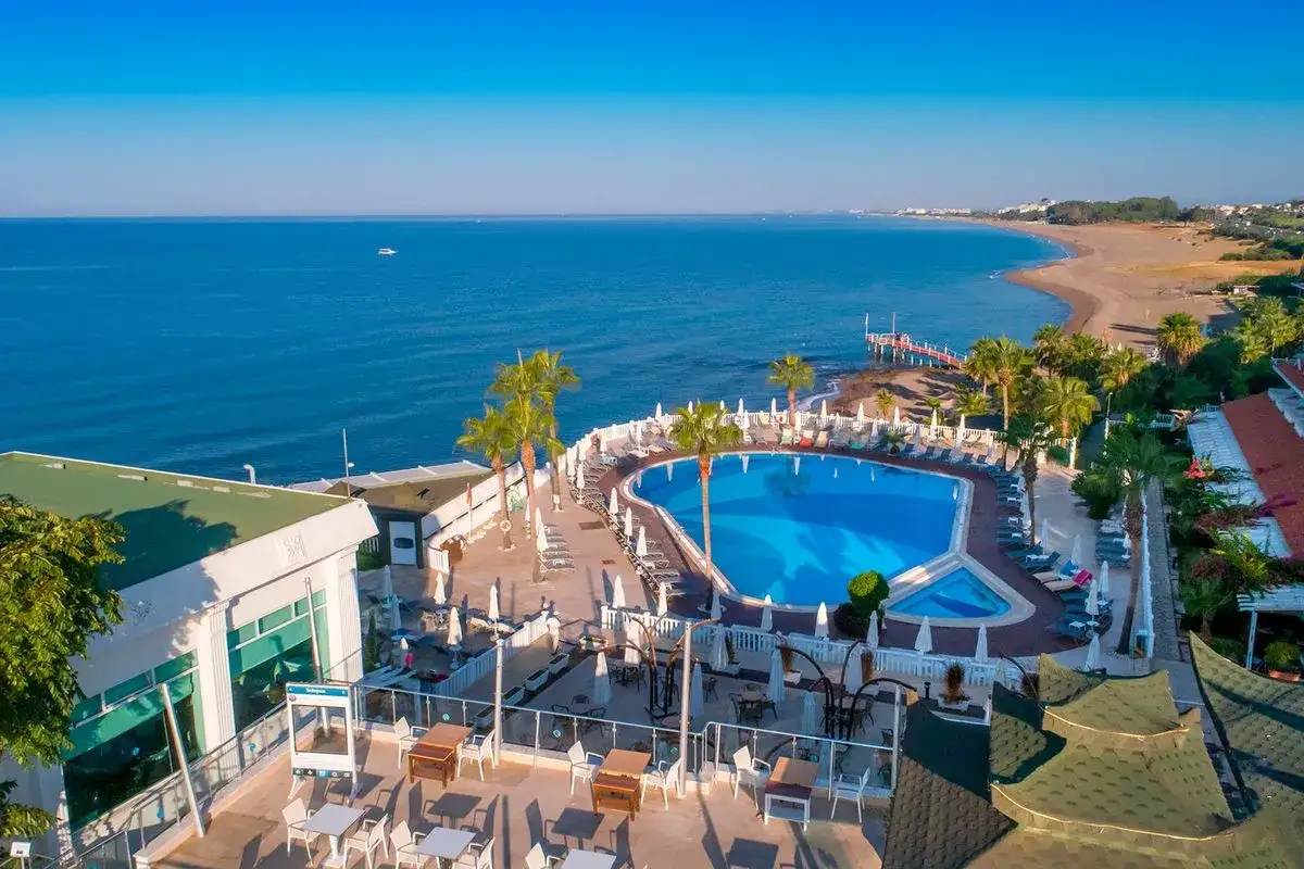 Luksusowy hotel z basenem i palmami, idealny na wakacje. Z okien widać piaszczystą plażę i błękitne morze. Można tu odpocząć i cieszyć się słońcem.